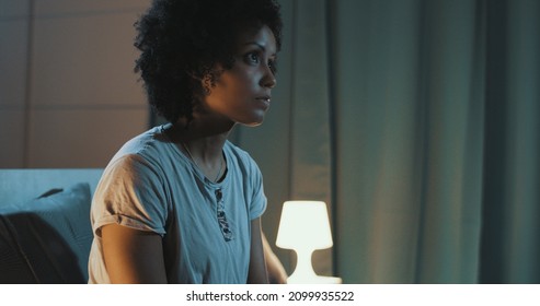 Sad African American Woman Sitting On Bed At Night, She Can't Sleep