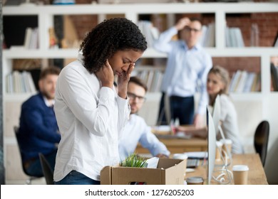 Sad African Female Young Employee Packing Belongings In Box At Workplace Got Fired From Job, Stressed Upset Black Worker Intern Leaving Office On Last Day At Work Crying After Unfair Dismissal