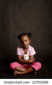 Sad African little girl alone on black background