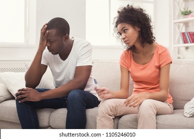Sad african-american couple after pregnancy test result, sitting on couch at home, man desperate and depressed, right contraception concept, copy space - Shutterstock ID 1105246010