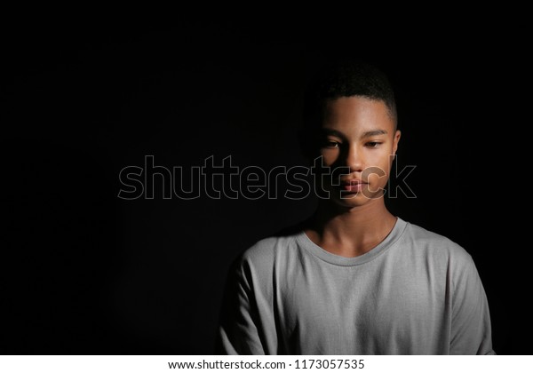 暗い背景に悲しいアフリカ系アメリカ人の10代の少年 の写真素材 今すぐ編集