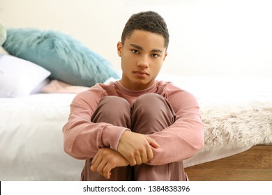 Sad African-American Teenage Boy Sitting In Bedroom