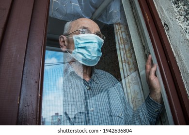 Sad aged man in face mask looking through glazing window surface. Concept lockdown during pandemic. - Powered by Shutterstock