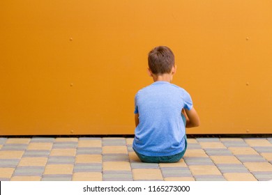 Sad Alone Boy Sitting Near Colorful Wall Outdoors