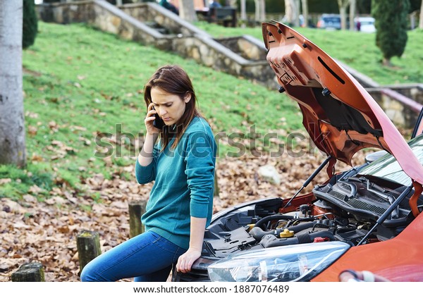 sad or angry beautiful woman calling insurance\
or tow truck for car engine breakdown. vehicle breakdown concept.\
roadside assistance