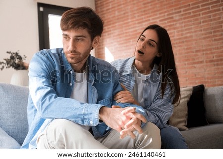 Sad and angry guy thinking about relationship problems sitting on sofa with offended girlfriend, conflicts in marriage, upset couple after dispute, making decision to break up and divorce