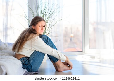 Sad And Angry Teenage Girl Sitting On The Floor In The Room. Teenager Problems Concept