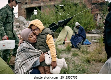 Sad Arabian Woman Hugging Daughter With Toy While Army Medic Moving With First Aid Box Behind Them In Ruined Town