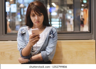 Sad Asia Woman Using Mobile Phone In Department Store.Sad Emotion Woman.