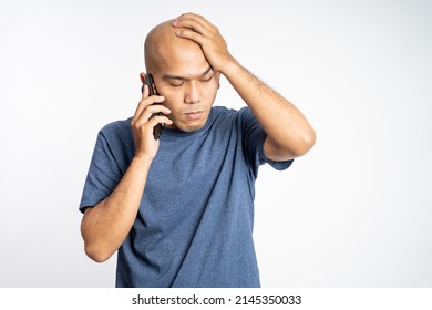 Sad Asian Bald Man Scratching Head While Listening To Phone