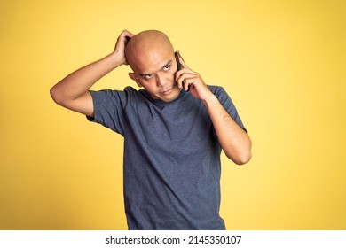 Sad Asian Bald Man Scratching Head While Listening To Phone