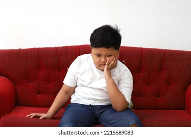 Sad Asian Boy Sitting On The Red Sofa