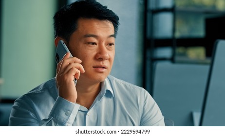 Sad Asian executive worker businessman manager middle-aged korean japanese chinese man answer mobile call work in office speak phone solve business problem distant conversation by 5g cell connection - Powered by Shutterstock