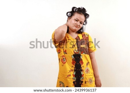 Sad Asian housewife having problem with her back neck, hand holding her neck
