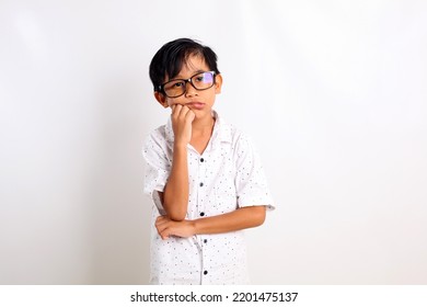 Sad asian little boy standing while holding his chin. Isolated on white background - Powered by Shutterstock