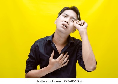 A sad asian man is crying and wiping away tears after having a problems. stressful man cries out loudly. a worker crying after losing his job. - Shutterstock ID 2276855007
