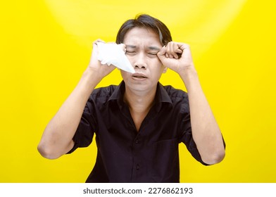 A sad Asian man is crying and wiping away tears after having problems using tissues. After losing his job, a man was seen crying deeply and wiping his tears with tissues.  - Shutterstock ID 2276862193