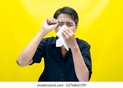 A sad Asian man is crying and wiping away tears after having problems using tissues. After losing his job, a man was seen crying deeply and wiping his tears with tissues.  - Shutterstock ID 2276862199