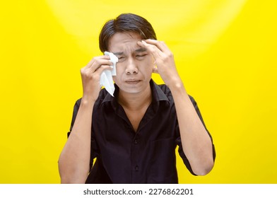 A sad Asian man is crying and wiping away tears after having problems using tissues. After losing his job, a man was seen crying deeply and wiping his tears with tissues.  - Shutterstock ID 2276862201