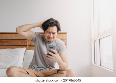 Sad Asian man has bad online chat news and feels disappointed on the smartphone.