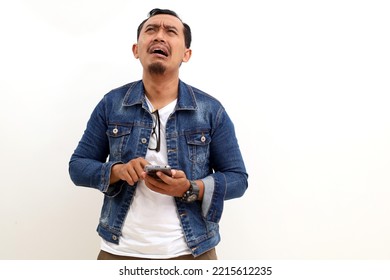 Sad Asian Man Standing While Holding A Cell Phone. Isolated On White Background