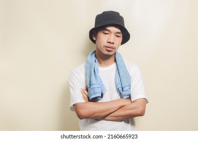 Sad Asian Man Wearing Bright White T-shirt With Black Hat Carrying Blue Towel On Isolated Background