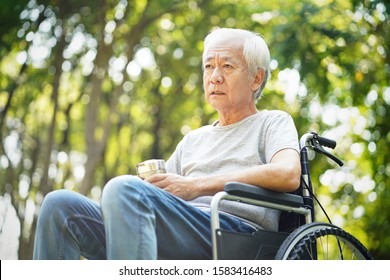 Sad Asian Old Man Sitting In Wheel Chair Outdoors