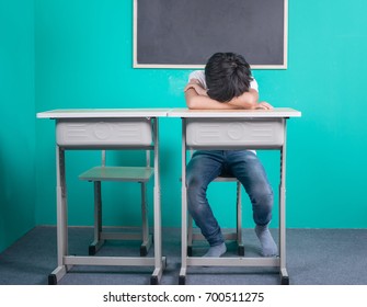 Sad Asian School Boy Sitting In Classroom