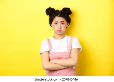 Sad Asian Teen Girl Sulking, Cross Arms On Chest, Pouting And Frowning, Complaining On Unfair Thing, Standing Against Yellow Background