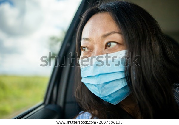 Sad Asian woman commute\
by taxi and she wear face mask to avoid infectious diseases\
coronavirus