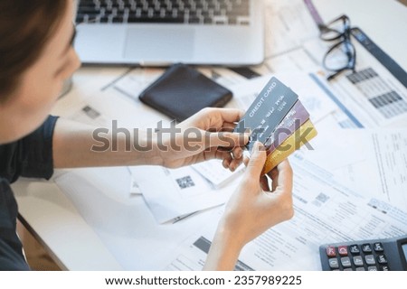 Sad Asian woman looking at many credit cards in her hand and worried about loan debt pay late.