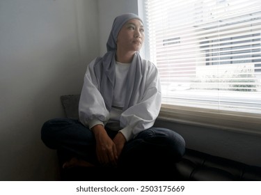 Sad Asian Woman Sitting Crossed Legs On Couch And looking Away At Window - Powered by Shutterstock