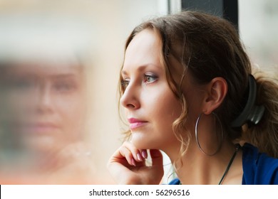 Sad beautiful woman looking through a window