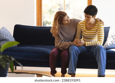 Sad biracial lesbian couple embracing and comforting, on couch in sunny living room, copy space. Depression, mental health, support, care, gay, relationship, togetherness and domestic life, unaltered. - Powered by Shutterstock