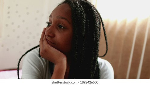 Sad black girl suffering from depression sitting in bed feeling worry and regret