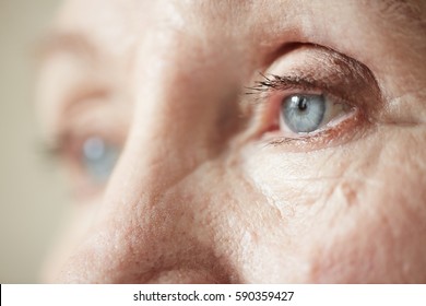 Sad blue-grey eyes of elderly woman looking to the side, extreme close-up shot - Powered by Shutterstock