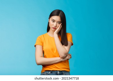 Sad bored asian female student attend boring uninteresting lecture lean face palm, look indifferent express apathy dislike, grimacing and sulking disappointed stand blue background bothered - Shutterstock ID 2021347718