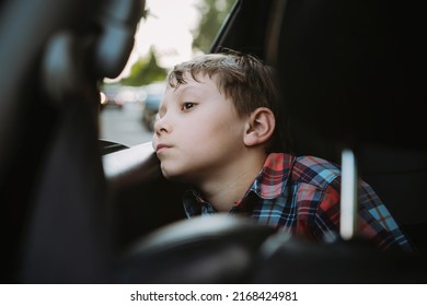Un chico caucásico aburrido y triste que viaja en auto sentado por la ventana abierta. 