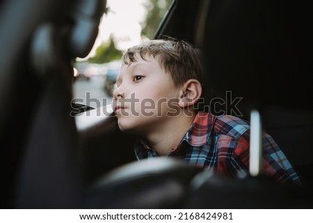 Sad bored caucasian boy travelling by car sitting by open window. 