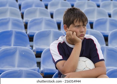 Sad Boy With A Ball On The Football Grandstand.