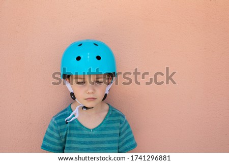 Sad boy in a Bicycle helmet for safety on a beige background. Lost the competition. The concept of children's sports