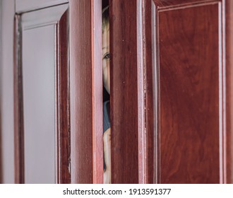 Sad Boy Hide In Closet, Close-up View Of Blue Eye In Ajar Door Slit Home Wardrobe. Child Emotions. Warning Symptom Sign, Treatment Help For Childhood Adolescent Depression Illness, Fears, Family Life