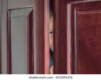 Sad Boy Hide In Closet, Close-up View Of Blue Eye In Ajar Door Slit Home Wardrobe. Child Emotions. Warning Symptom Sign, Treatment Help For Childhood Adolescent Depression Illness, Fears, Family Life