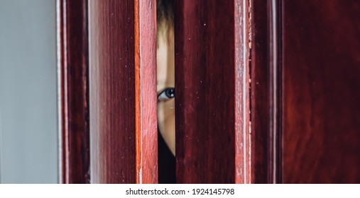 Sad Boy Hide In Closet, Close-up View Of Blue Eye In Ajar Door Slit Home Wardrobe. Child Emotions. Warning Symptom Sign, Treatment Help For Childhood Adolescent Depression Illness, Fears, Family Life