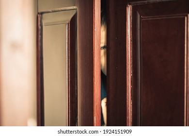 Sad Boy Hide In Closet, Close-up View Of Blue Eye In Ajar Door Slit Home Wardrobe. Child Emotions. Warning Symptom Sign, Treatment Help For Childhood Adolescent Depression Illness, Fears, Family Life