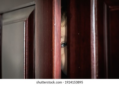 Sad Boy Hide In Closet, Close-up View Of Blue Eye In Ajar Door Slit Home Wardrobe. Child Emotions. Warning Symptom Sign, Treatment Help For Childhood Adolescent Depression Illness, Fears, Family Life