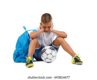 A sad boy isolated on a white background. Tired kid with a bright satchel and a soccer ball. A troubled child. Copy space.