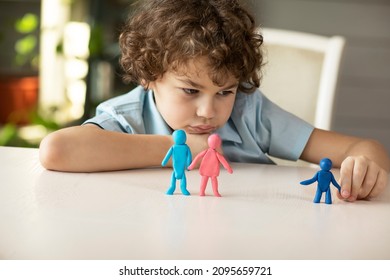 A sad boy plays with plasticine figurines of a family where parents and child are separate, the concept of abandoned children, adoption. High quality photo