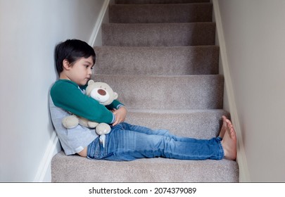 Sad Boy Sitting Alone On Staircase With Teddy Bear, Lonely Kid Looking Dow With Sad Face Not Happy To Go Back To School, Depressed Child Boy Sitting In The Corner Of A Stair,Mental Health