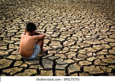 Sad a boy sitting on dry ground .concept hope and drought